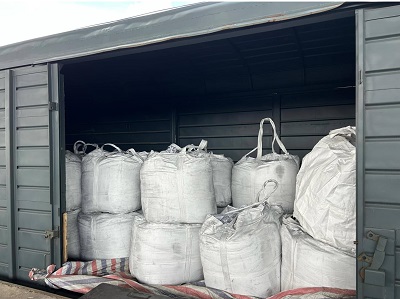 White 1-ton bulk bags of Calcium Silicon alloy stacked neatly inside open rail wagon car with waterproof tarpaulin on floor for Central Asia transit